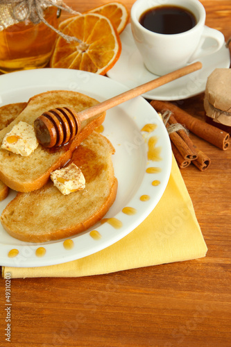 White bread toast with honey and cup of coffee on wooden table