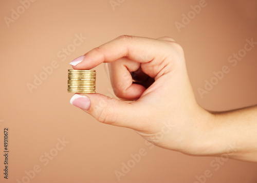 Woman hands with coins on brown background