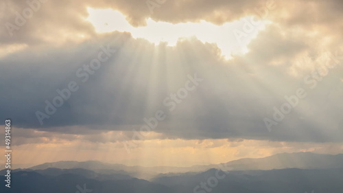 Time Lapse. Sun rays pass through the clouds over the mountains.