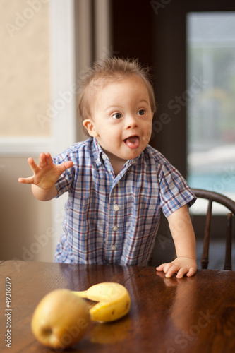 Quadro su tela Down Syndrome child reaching for fruit on table
