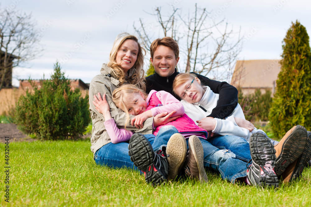 Eine Familie sitzt zusammen auf einer Wiese Eine Familie sitzt zusammen auf einer Wiese