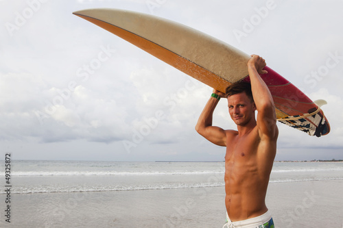 Strong professional surfer raising up his surf board