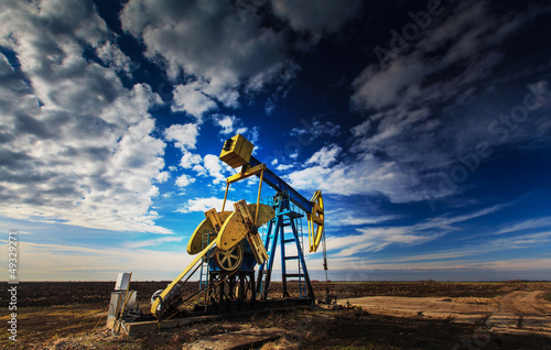 Operating oil well profiled on dramatic cloudy sky photo