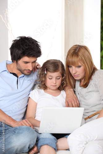 couple with daughter and laptop on sofa
