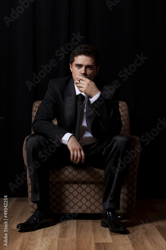 Man with cigarette sitting in vintage armchair © Masson