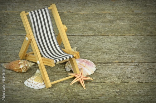 Canvas Print A deckchair and seashells on a wooden background