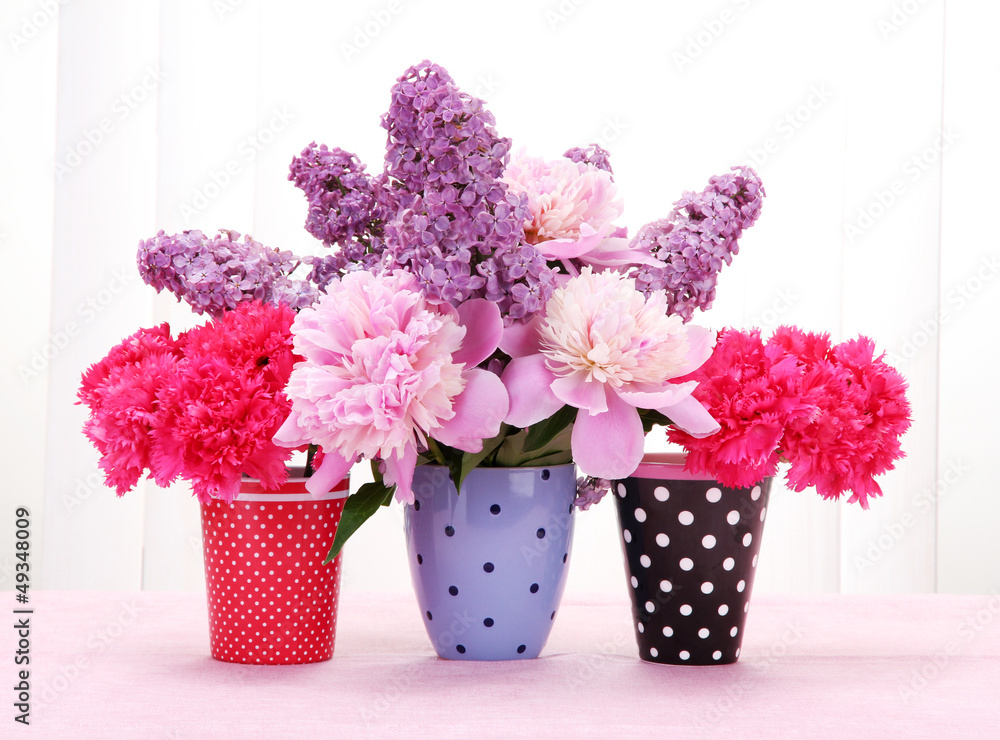 Obraz spring flowers in cups on table on white wooden background