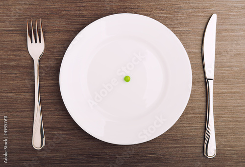 diet concept. one pea on an empty white plate