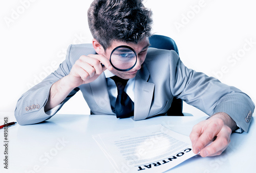 Businessman with magnifying glass reading the fineprint in a con photo