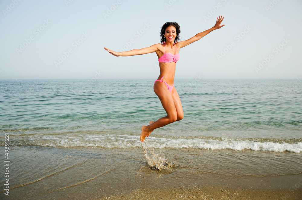 Woman with beautiful body jumping in a tropical beach Woman with beautiful body jumping in a tropical beach