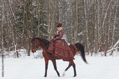 Eleganny woman in riding habit sits astride a bay Arab racer