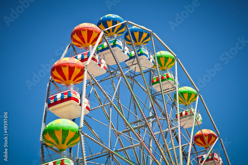 Obraz na plátně Close-up of colorful ferris wheel on vivid blue sky