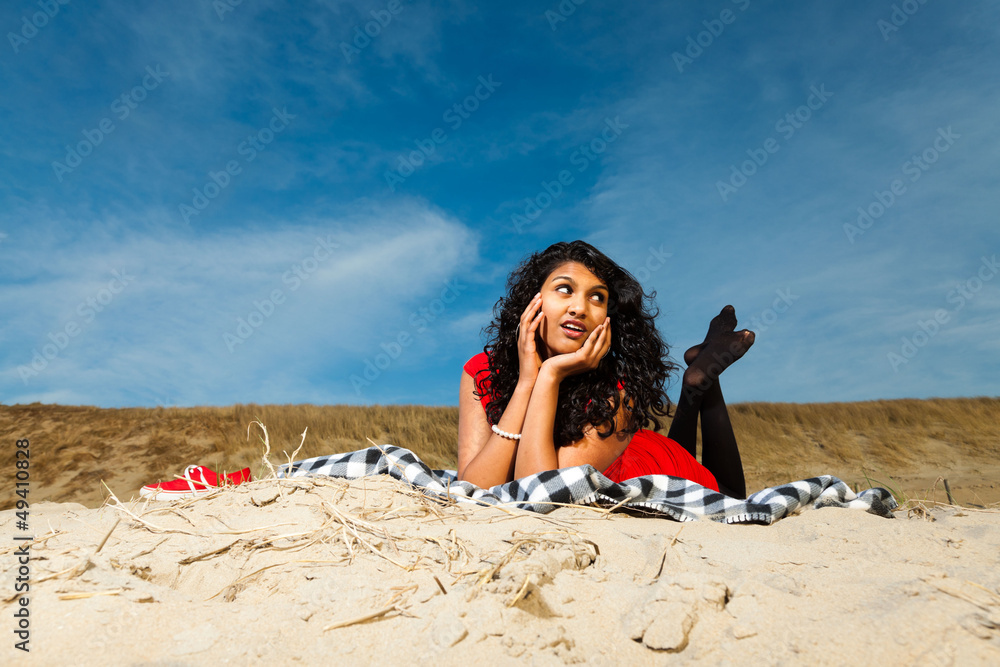 Indian girl with long hair dressed in red on the beach in summer
