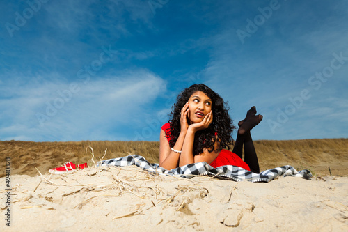 Indian girl with long hair dressed in red on the beach in summer