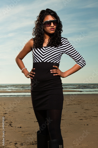 Pretty indian girl with sunglasses on the beach in summer.