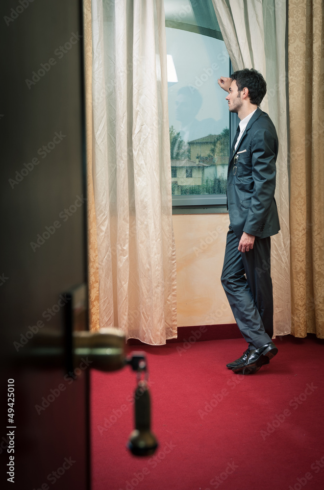 Lonely man at the window inside hotel room. Lonely man at the window inside hotel room.