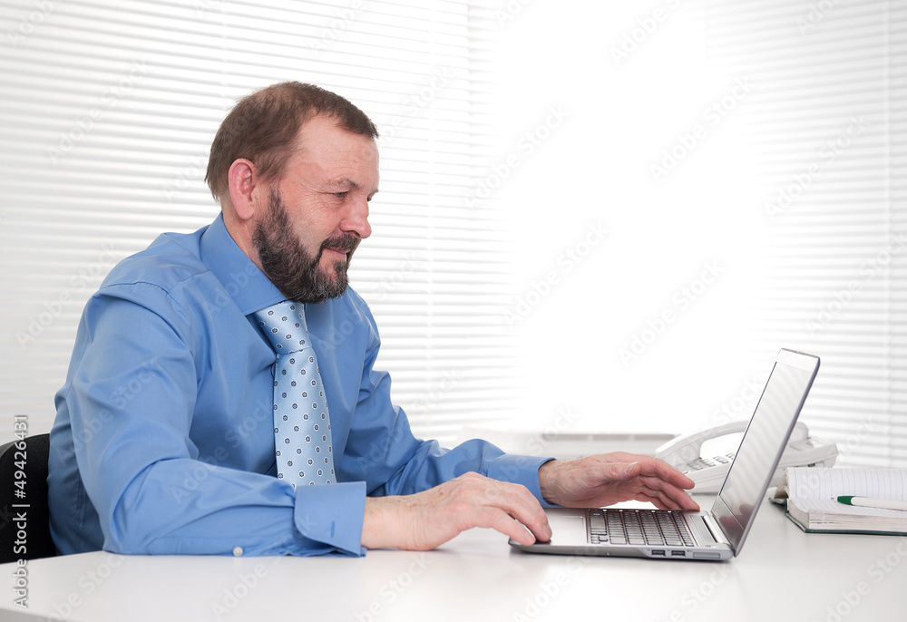 senior business man sitting by his laptop in the office senior business man sitting by his laptop in the office