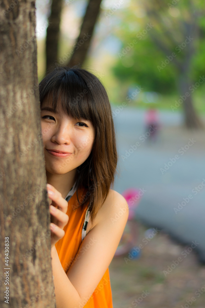 Cute Thai girl hiding behind the tree Cute Thai girl hiding behind the tree