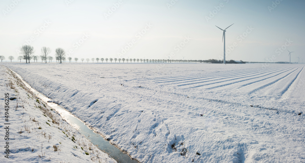 Wind turbine in a snowy field in sunlight