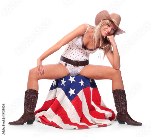 Young cowgirl sitting on a american flag. Feminism concept.
