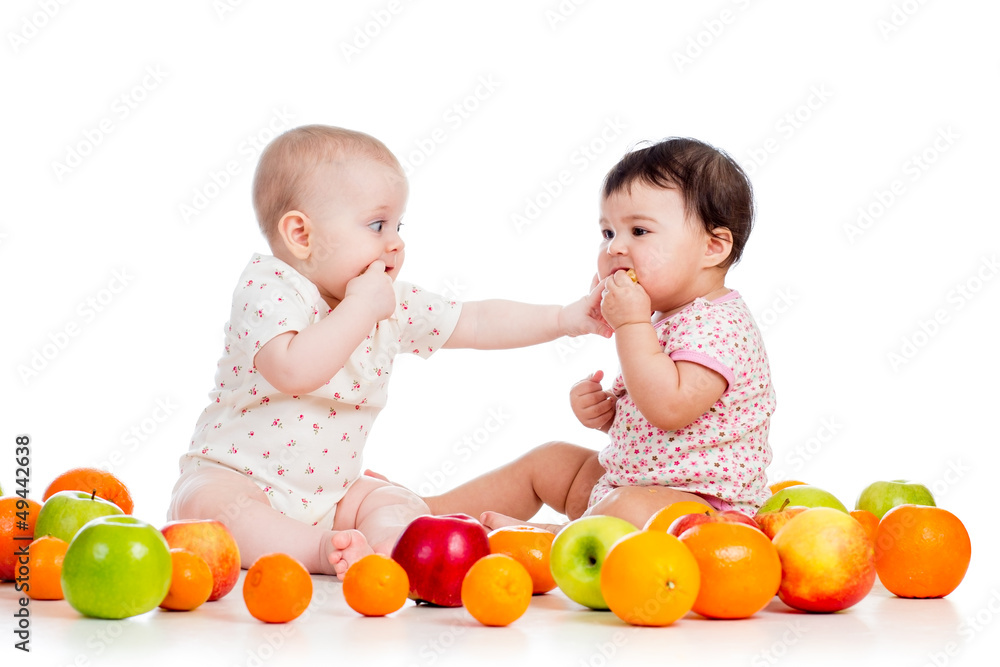 Funny children babies with healthy food fruits isolated on white Funny children babies with healthy food fruits isolated on white