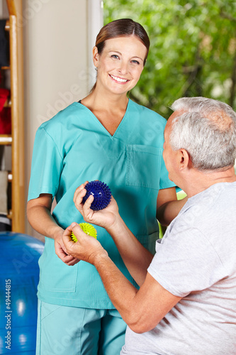 Physiotherapeutin zeigt Übung mit Igelball photo