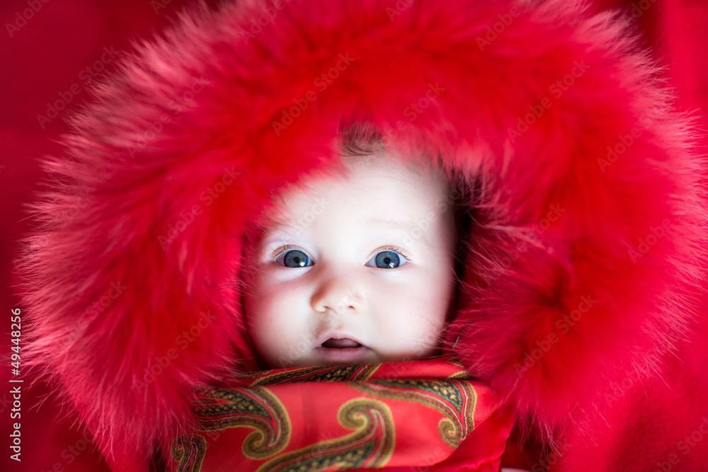 Baby girl with big blue eyes wearing a red jacket Stock Photo