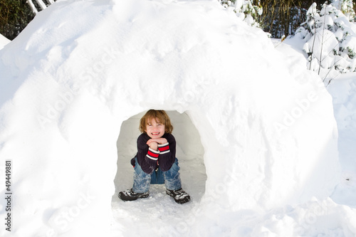 Funny boy playing in a snow igloo