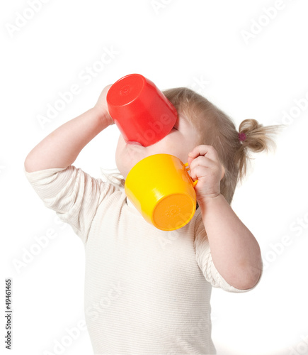 Child drinks juice from a mug.