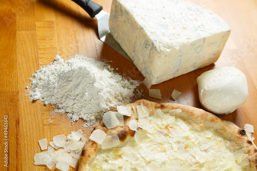 Italian Pizza, ingredients in the background on a wood table