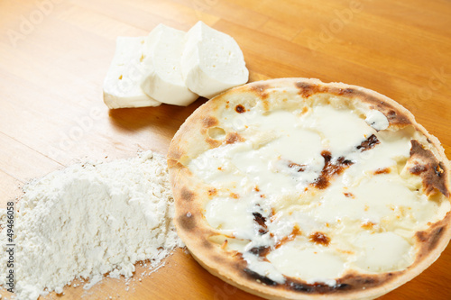 Typical Italian Pizza, ingredients in background on wood table