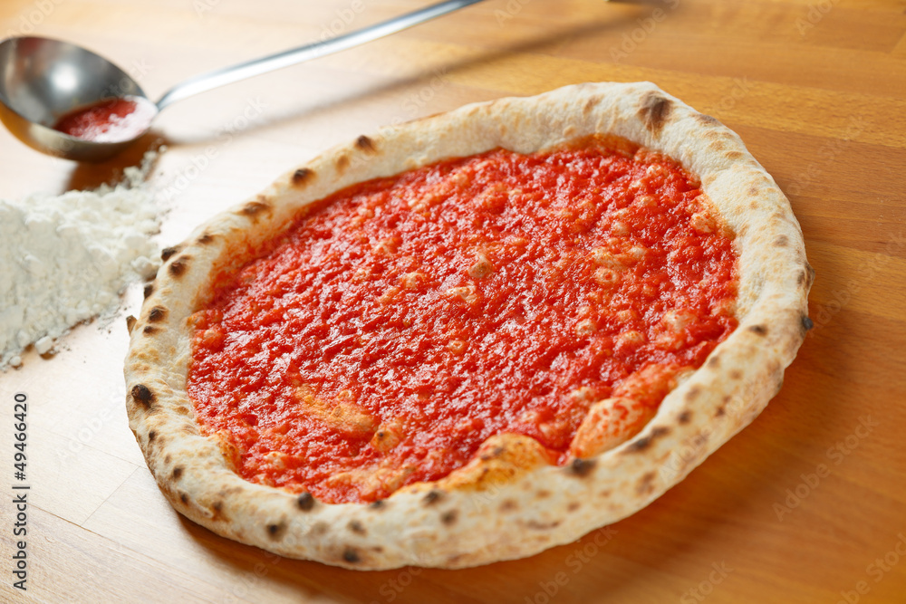 Italian Pizza, ingredients in the background on a wood table Italian Pizza, ingredients in the background on a wood table