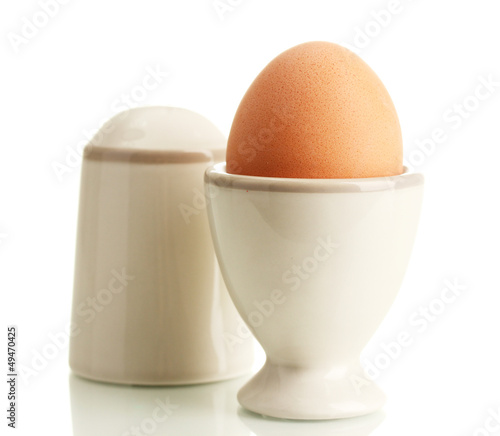 Whole boiled egg in egg cup and salt, isolated on white