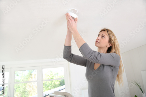 Woman setting up fire alarm inside house