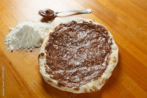 Italian Pizza, ingredients in the background on a wood table