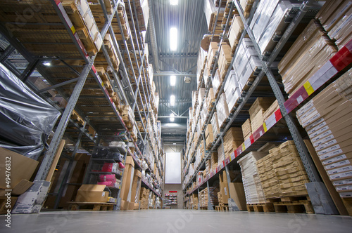 Rows of shelves with cardboard boxes on modern warehouse in stor