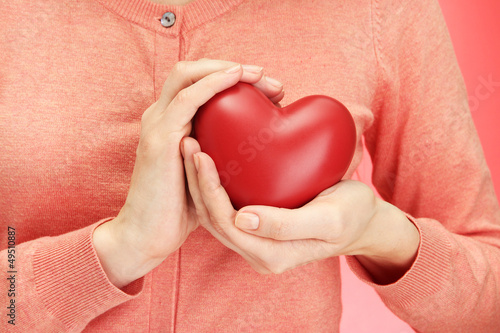 Fototapeta Naklejka Na Ścianę i Meble -  Red heart in woman hands, on red background