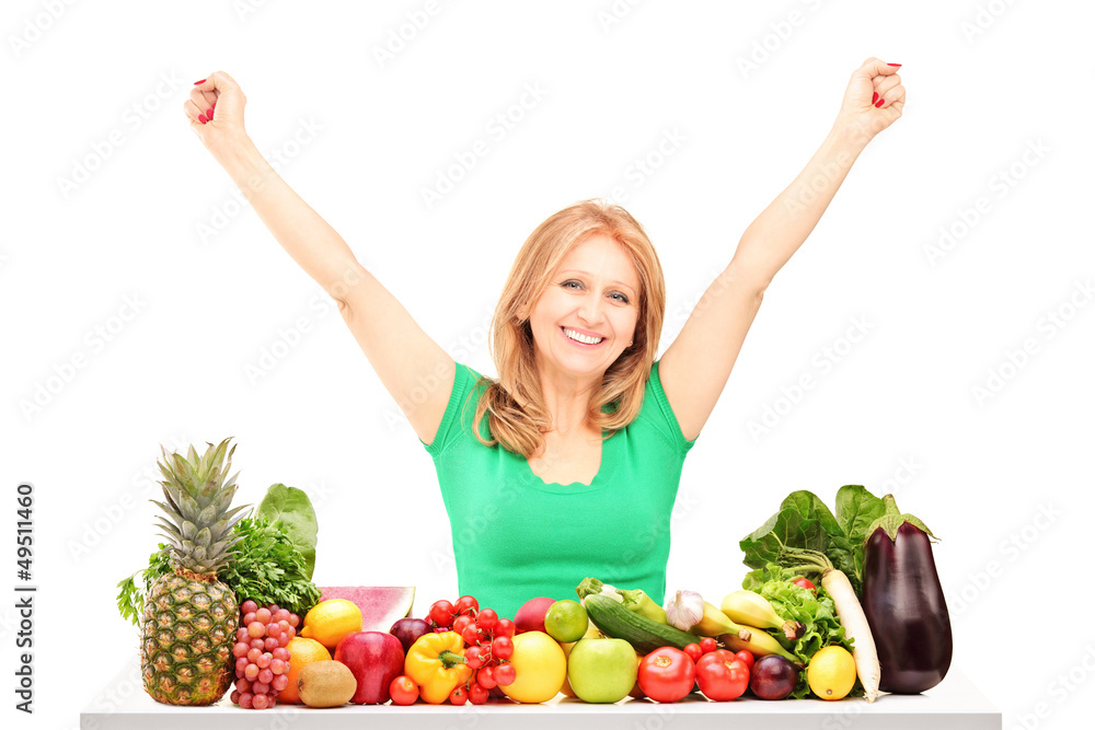 Happy woman with raised hands posing with pile of fruits and veg Happy woman with raised hands posing with pile of fruits and veg