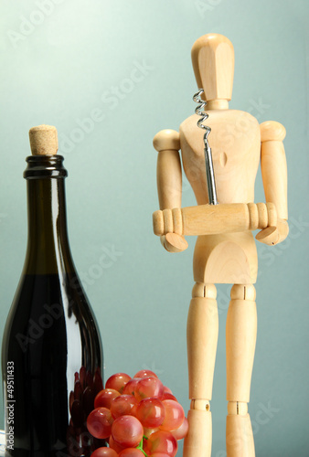 Mannequin with corkscrew and wine bottle, on grey background