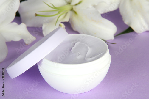 Fototapeta Naklejka Na Ścianę i Meble -  Cosmetic cream and beautiful lily, on purple background