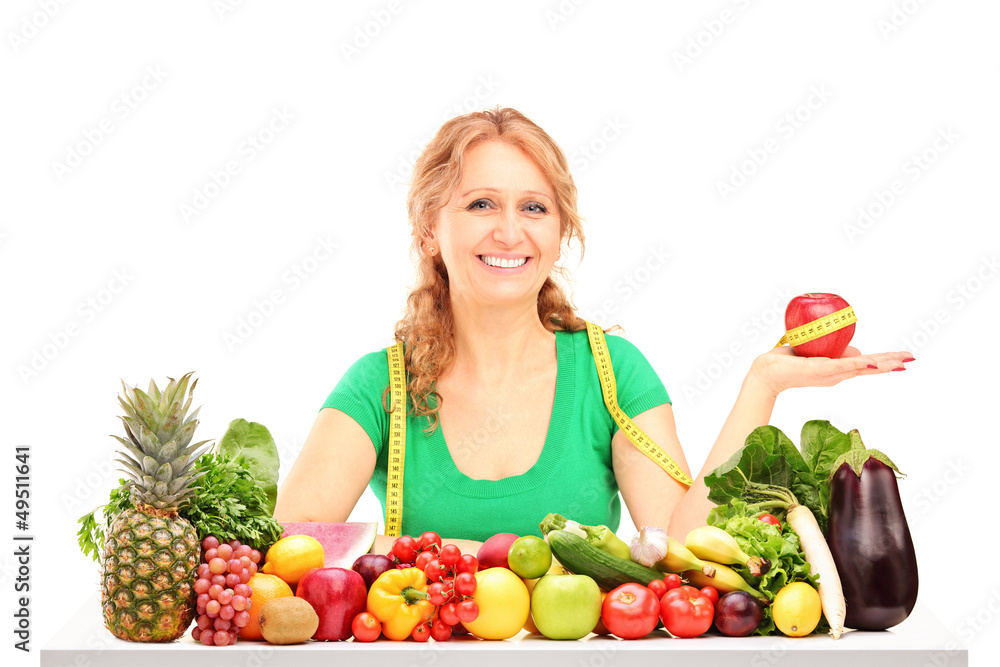 Smiling woman with fruits and vegetables holding an apple with m Smiling woman with fruits and vegetables holding an apple with m
