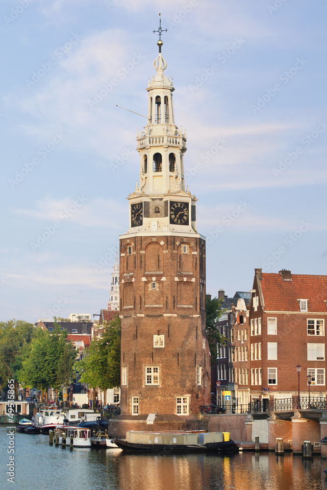 Ancient tower with clock in the historical city center of Amsterdam in the early morning.
