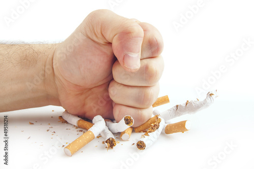 Human fist breaking cigarettes on white background