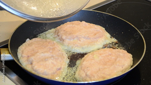 baking potatoes pancakes with meat. hand open pan cover photo