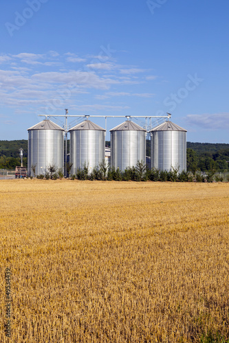 four silver silos in the field after the harvest