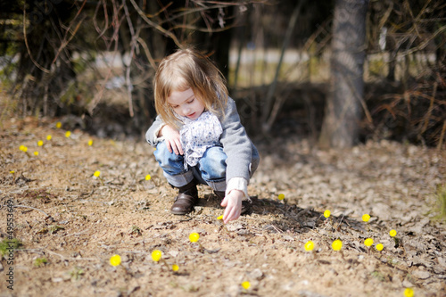 Little toddler girl touching spring flowers © MNStudio