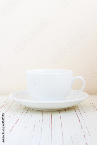 Coffee cup on white wooden table over bright background