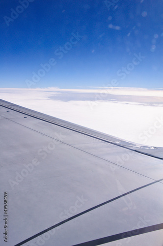 View from window seat of an airplane overlooking blue sky and cl