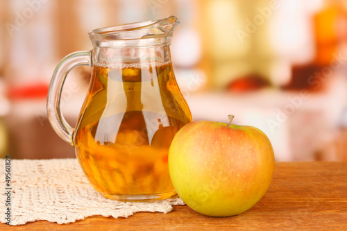 Full jug of apple juice and apple