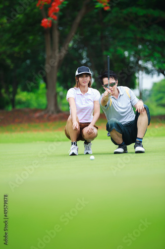 Professional teaching young woman golfer